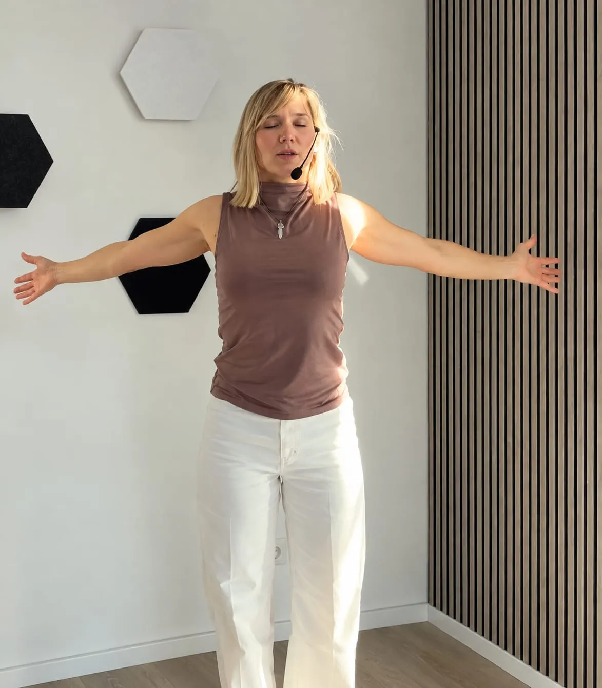 Laura Jung leitet eine Atemübung an: Arme weit geöffnet, Augen geschlossen, mit Headset