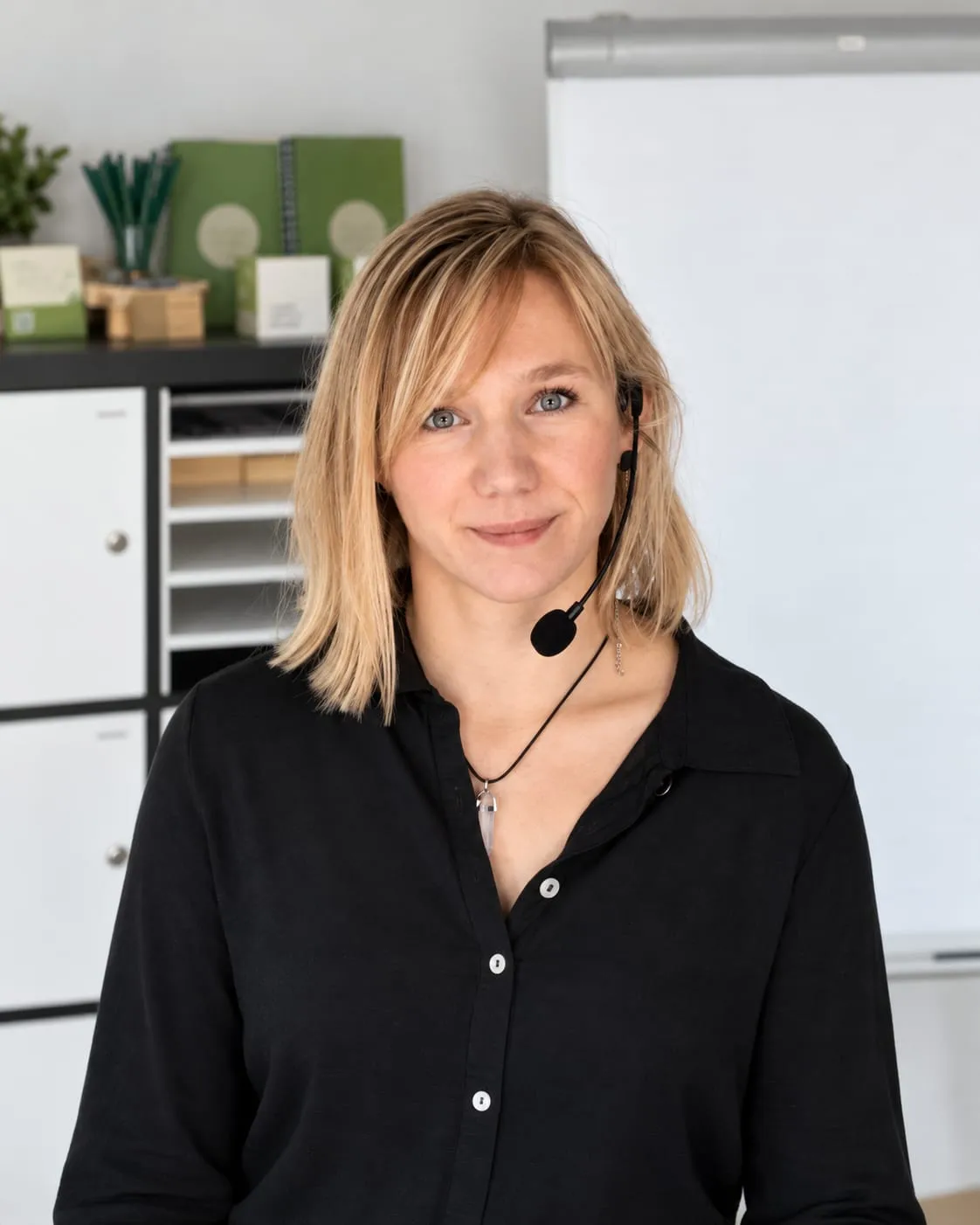 Porträt von Laura Jung mit Headset in einem Büro, im Hintergrund ein Flipchart
