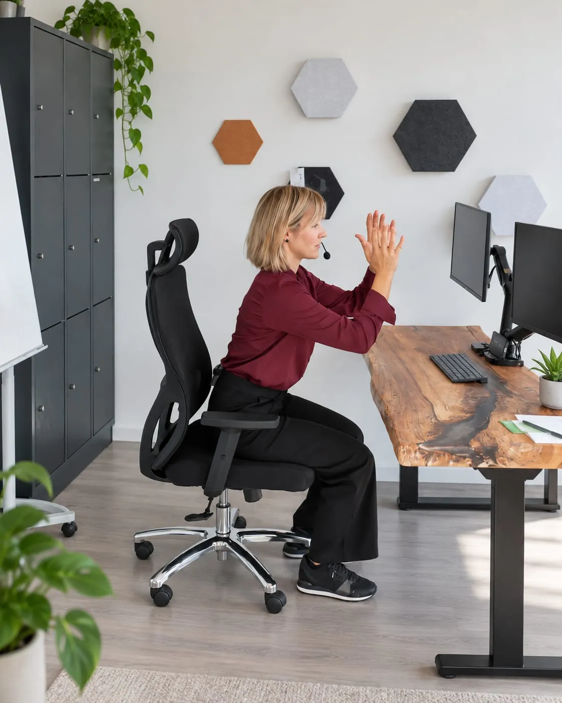 Laura Jung zeigt im Büro am Schreibtisch eine Dehnübung für Arme und Schultern